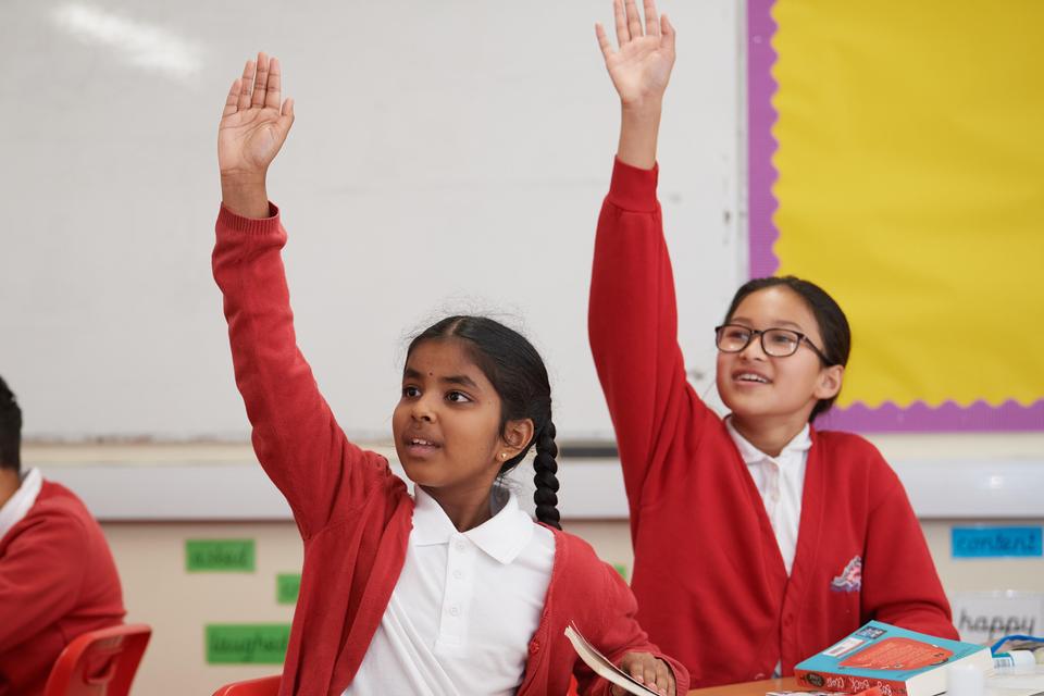 Children with their hands up in class